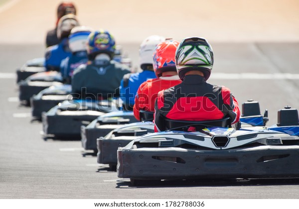 Go kart drivers with\
colorful helmets