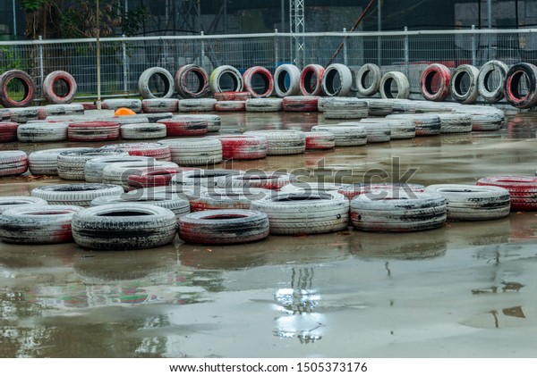 Go Kart Karting Circuit Race Track\
with white red tyres as buffer in the rain wet\
ground
