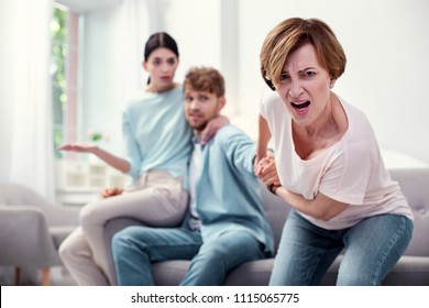 Go with me. Unhappy angry mother holding her sons hand while wanting his attention