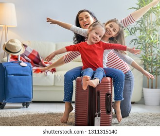 Go on an adventure! Happy family preparing for the journey. Mom and daughters are packing suitcases for the trip.