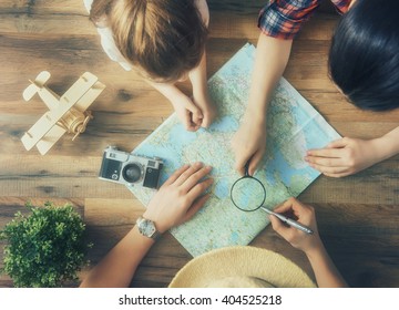 Go On An Adventure! Happy Family Preparing For The Journey. Mom, Dad And Daughter Study The Map And Choose A Route Of Travel.