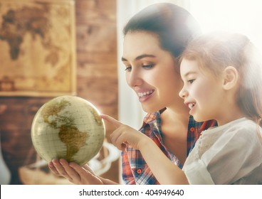 Go on an adventure! Happy family preparing for the journey. Mom and daughter study the globe and choose a route of travel. - Powered by Shutterstock