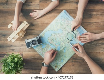 Go On An Adventure! Happy Family Preparing For The Journey. Mom, Dad And Daughter Study The Map And Choose A Route Of Travel.