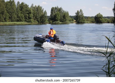 Go Out Inflatable Motor Boat With Outboard Motor And Happy Man In Orange Lifejacket On Tiller Fast Floating On Water On Green Forest Background At Sunny Summer Day, Beautiful European Lake Landscape