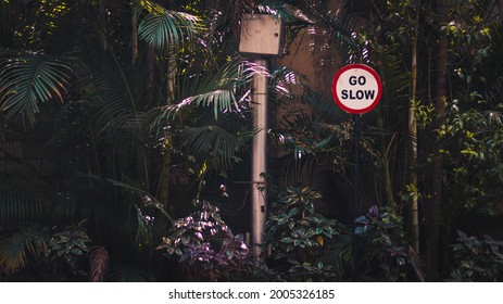 A Go Slow Sign Board Amidst The Plants