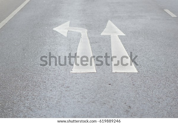 Go straight or turn left traffic sign painted on\
paved road.