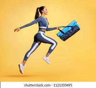 Go To Training. Sporty Woman With Bag Running In Silhouette On Yellow Background. Dynamic Movement. Side View. Sports And Healthy Lifestyle