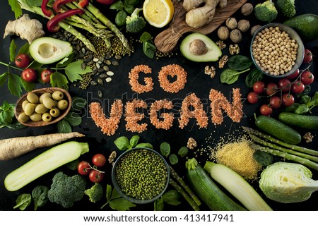 Go vegan concept with lettering. variety of fresh green organic vegetables & lentils on dark background. Vegan food concept.
