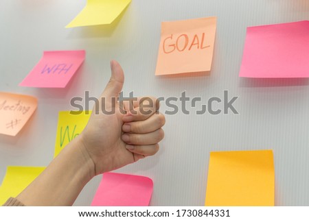 Goal. business woman showing thumbs up with colored sheets sticky note paper on white board background in office, business meeting, brainstorming, creative, digital online marketing, financial concept