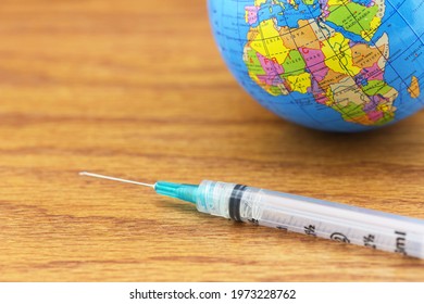 Goal Of Global Vaccine Distribution And Equity Seen In Symbols Of Syringe And Globe On Wood Grain Background With Copy Space. 