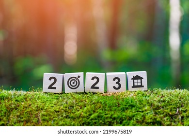 Goal House 2023. Wooden Cubes With Numbers 2023, Target And House Icon On Mossy Fallen Tree In Summer Forest In Focus. Background Blurred.