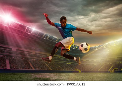 Goal. Male african soccer football player jumping in attack during sport match on cloudy sky background at stadium with flashlights. Sport competition. Action, motion, energy and dynamic concept. - Powered by Shutterstock