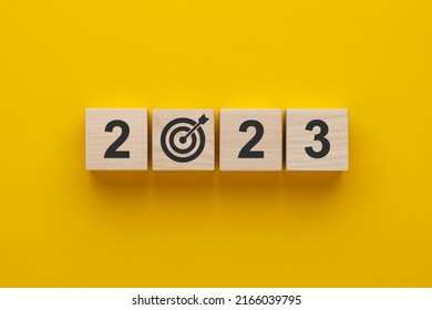 Goal in the new year 2023. Wooden cubes with numbers 2023 and target icon on yellow background. Business development strategy, advancement and goal concept. - Shutterstock ID 2166039795