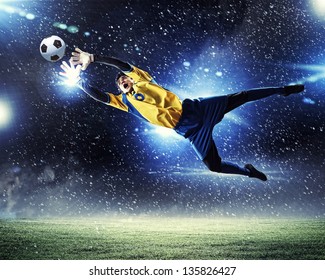 Goalkeeper catches the ball . At the stadium, in the spotlight. - Powered by Shutterstock