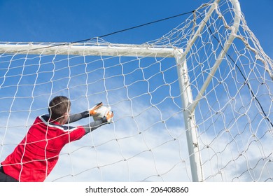 Goalkeeper in red making a save on a clear day - Powered by Shutterstock