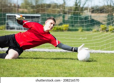Goalkeeper in red saving a goal during a game on a clear day - Powered by Shutterstock