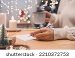 Goals plans make to do and wish list for new year christmas concept, girl writing in notebook. Woman hand holding pen on notepad at home on winter holidays xmas. Christmas decoration, gift boxes. 