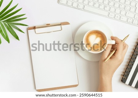  Goals, resolution, ideas, notes or plan writing concept. Female hand holding cup of coffee. Empty blank paper on clipboard. Top view. Space for text.	