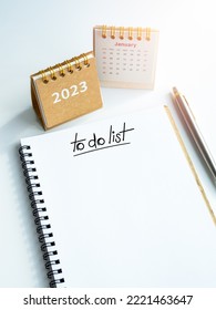 Goals and target concept in new year 2023. To do list, text on white blank space on spiral notepad, vertical style with pen and 2023 year desk calendar cover with January page on white background.
