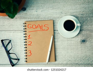 goals text on notepad with coffee and glasses on table - Shutterstock ID 1251024217