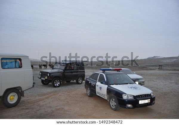 GOBI DESERT, MONGOLIA - CIRCA OCTOBER 2007:
Police car, Russian van, Jeep, horses, and outhouse in front of
