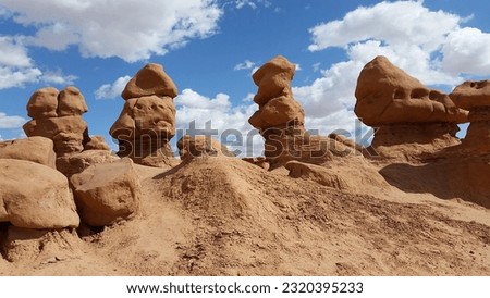 Goblin hoodoo rock formations against a blue sky with bright white clouds at Goblin Valley State Park in Utah
