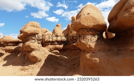 Goblin hoodoo rock formations against a blue sky with bright white clouds at Goblin Valley State Park in Utah