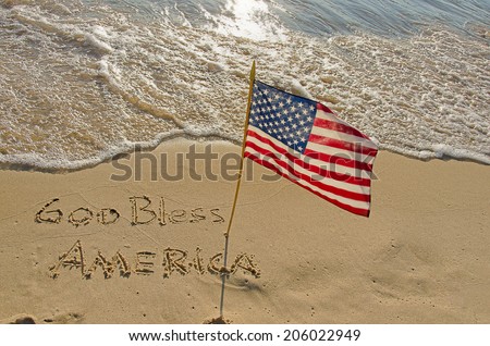 God Bless America written in beach sand with American flag