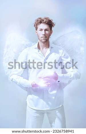 God of love Cupid. Courageous handsome male Cupid angel in white clothes and with white wings. White background. Valentine's Day.