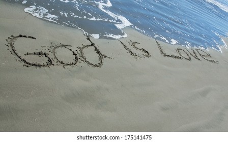 God Is Love Written In Sand As The Waves Wash Close To It.