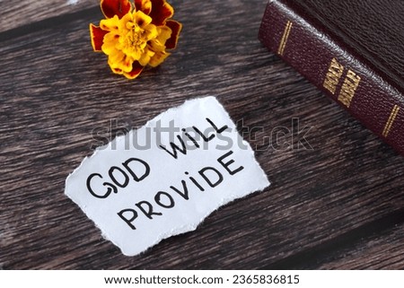 God will provide, handwritten biblical quote on wooden table with holy bible and flower. Close-up. God's promise, blessing, and care. Inspiring Christian message. Biblical concept.