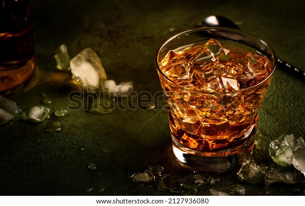Godfather alcoholic cocktail with scotch whiskey,\
amaretto liqueur and ice. Dark bar counter background, bar tools,\
copy space