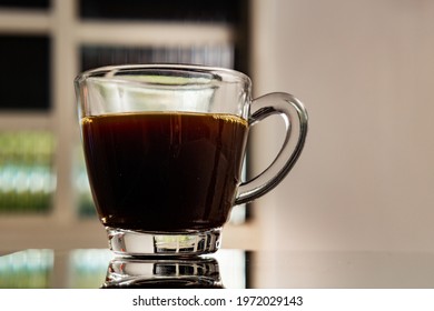 GOIANIA GOIAS BRAZIL - MAY 11 2021:  A Clear Glass Cup With Coffee On A Reflective Surface.