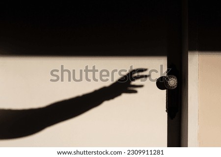 GOIANIA GOIAS BRAZIL - MAY 17 2023: The shadow of an arm with a hand trying to open a closed white door.