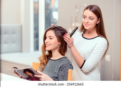 Going for a change of style. Young beautiful woman discussing hairstyling with her hairdresser holding a comb and scissors while sitting in the hairdressing salon - Shutterstock ID 256912663