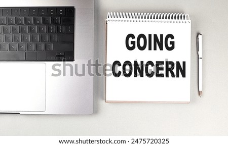 GOING CONCERN text on a notebook with laptop and pen . 