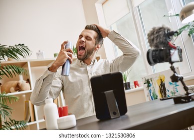 Going Crazy! Joyful Male Beauty Blogger Playing With Hair Spray While Recording Video Blog Episode For Youtube