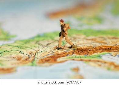 Going The Extra Mile In Business, Macro Of A Miniature Model Businessman With Briefcase Striding Across A Map, Concept With Shallow DOF.