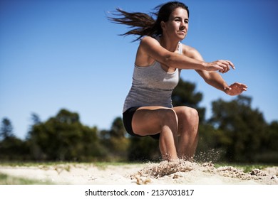 Going As Far As She Can. A Young Woman Doing Long Jump.