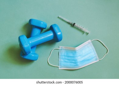 Going To Gym After Covid Vaccine Flat Lay Photo. Dumbbells, Disposable Mask And Syringe