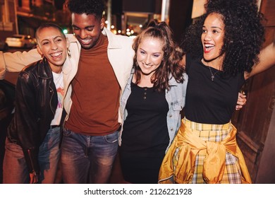 Going Out On A Friday Night. Group Of Vibrant Young People Laughing Happily While Walking Together In The City At Night. Multicultural Friends Having A Good Time On The Weekend.