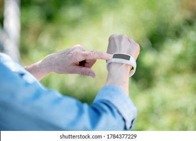 Going outdoor. An elderly woman using a smartwatch to track her pulse