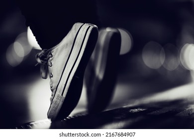 Going Over The Edge. Cropped Image Of A Person Wearing Sneakers Standing On Their Toes In The Street.