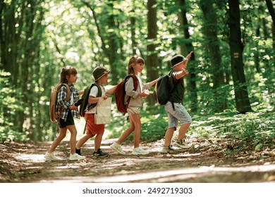 Going to the side. Kids in forest at summer daytime together. - Powered by Shutterstock