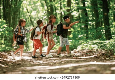 Going to the side. Kids in forest at summer daytime together. - Powered by Shutterstock