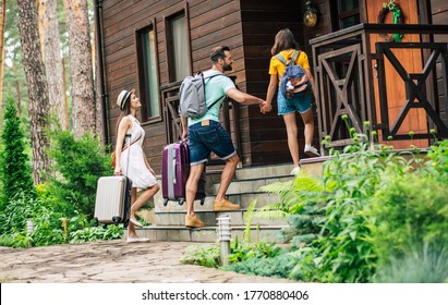 Going Up Stairs. A Photo Of A Smiling Travelling Summer Dressed Family With Suitcases And Backpacks Coming To The Hotel, Going Up Stairs.