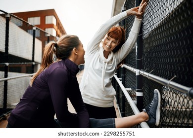 Going through their warm down. two attractive young women stretching before their run in the city.