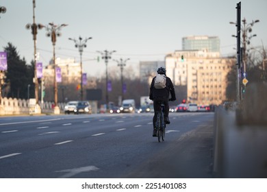 Going to work by bike. Photo with a biker from behind commuting to work on a bike in the middle of a city. Eco friendly transportation concept image. - Powered by Shutterstock