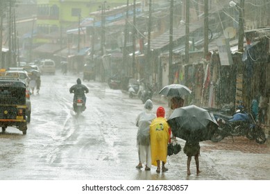 Gokarna-Mahabaleshwar, Karnataka, India - June 13 2019: In This Ancient Pilgrim Town, School Chidren In Rainy Wear Pass Through A Street Lined With Quaint Houses During Heavy Monsoon Showers.   