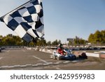 Go-kart driver crossing at finish line moving to checkered racing flag